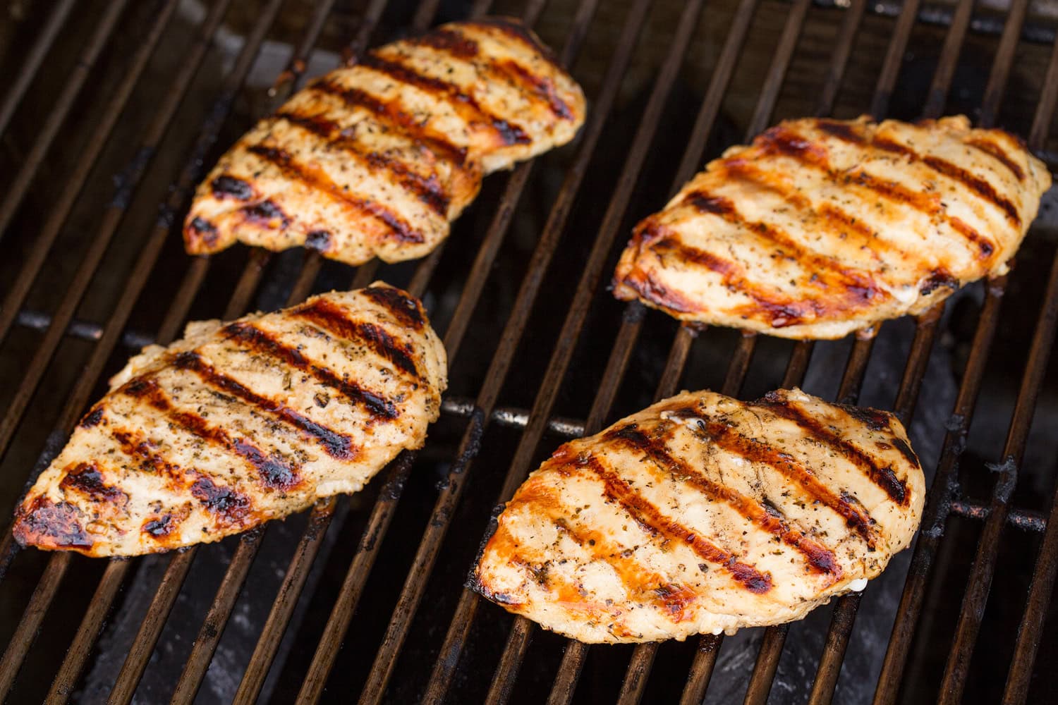 Four chicken breasts on the grill.
